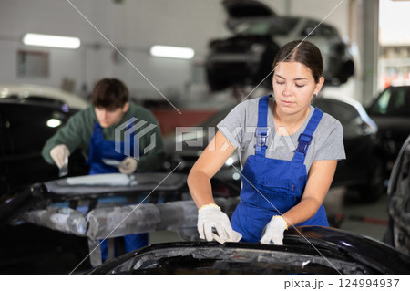Young female mechanic polishes car with sponge Young female mechanic polishes car with sponge 124994937