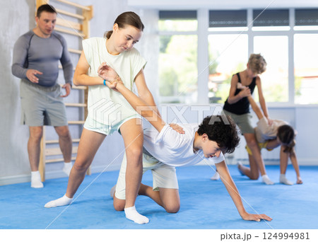 Girls and boys learns to do power grip with trainer during a self-defense lesson in gym Girls and boys learns to do power grip with trainer during a self-defense lesson in gym 124994981