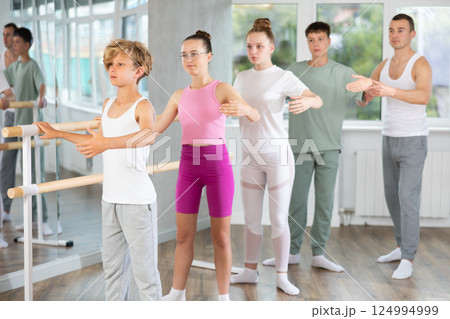 Group of teenagers practice ballet moves in classical dance studio 124994999