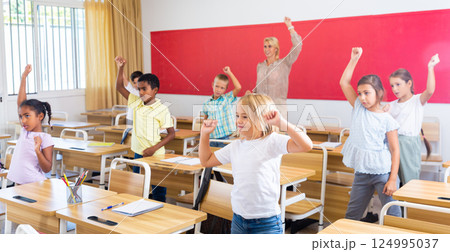 Preteen pupils doing warm-up in class with teacher at lesson 124995037