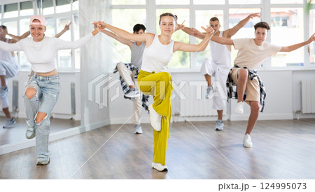 Teenage girl practicing hip hop reject step in training hall 124995073