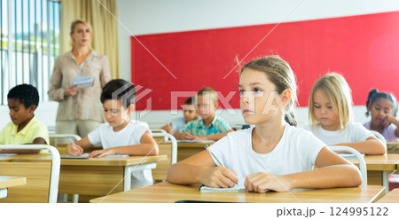 Portrait of girl who is posing at the desk in classroom elementary school Portrait of girl who is posing at the desk in classroom elementary school 124995122