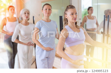 Slender women practicing ballet at ballet barre 124995123