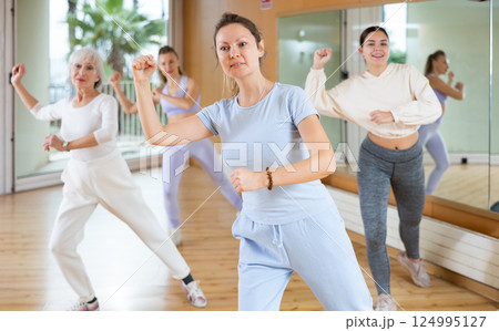 Active middle-aged woman practicing aerobic dance in training hall Active middle-aged woman practicing aerobic dance in training hall 124995127