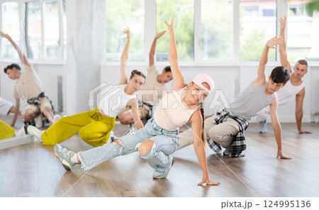 Group of teenagers in stylish clothes are training to dance low break and hip-hop in studio Group of teenagers in stylish clothes are training to dance low break and hip-hop in studio 124995136