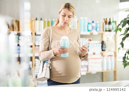 Pregnant woman chooses shampoo at pharmacy 124995142
