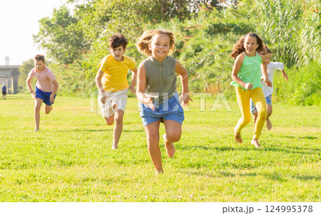 Happy preteen friends running together on green meadow Happy preteen friends running together on green meadow 124995378