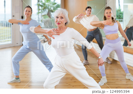 Dynamic elderly woman practicing aerobic dance in training hall 124995394