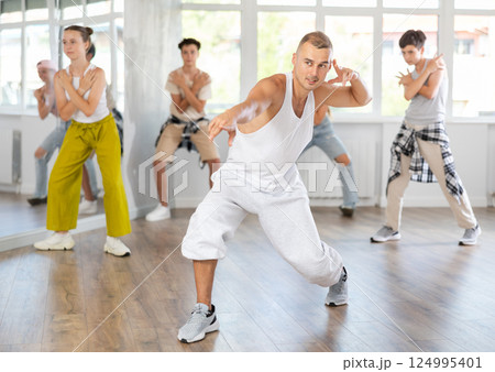 Male trainer dancing hip hop with group of teenagers Male trainer dancing hip hop with group of teenagers 124995401