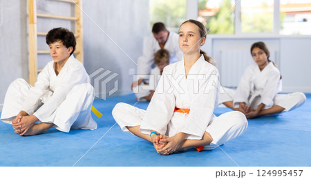 Children before training martial arts performs stretching butterfly 124995457