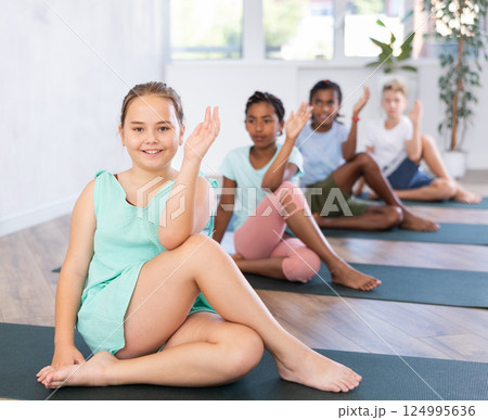 Preteen children exercising yoga in pose Gomukhasana in fitness center 124995636