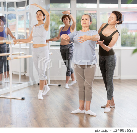 Ballet lesson for amateurs - choreographer teaches women of different ages different ballet steps in studio Ballet lesson for amateurs - choreographer teaches women of different ages different ballet steps in studio 124995658