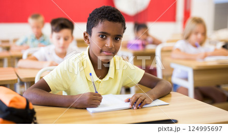 Smiling african preteen schoolboy looking at camera in class Smiling african preteen schoolboy looking at camera in class 124995697