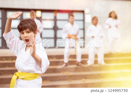 Boy in kimono doing karate moves in foreground 124995730