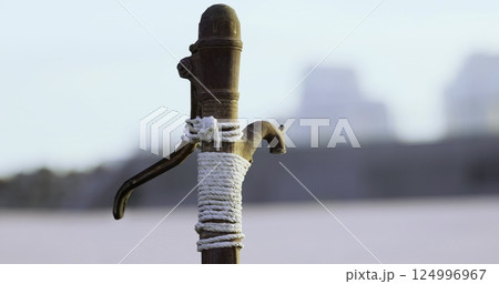 Old wooden post secured with rope at riverbank during calm evening Old wooden post secured with rope at riverbank during calm evening 124996967