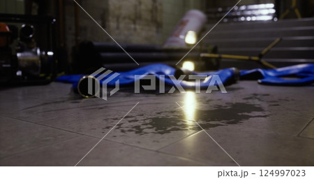 Water pooling on floor with equipment scattered in dimly lit area Water pooling on floor with equipment scattered in dimly lit area 124997023
