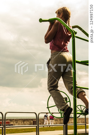 Active woman exercising on ladder outdoor. 124997150