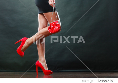 Girl in black short dress red spiked shoes holds handbag Girl in black short dress red spiked shoes holds handbag 124997151