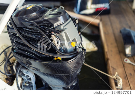 Repairing inflatable motorboat engine at boat garage. Ship engine seasonal service and maintenance. Vessel motor with open cover 124997701
