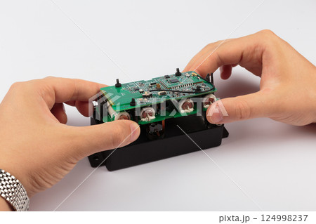 Hands of a master holding an electronic board on a 124998237