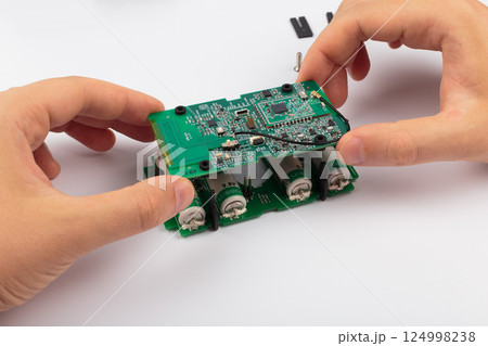 Hands of a master holding an electronic board on a 124998238