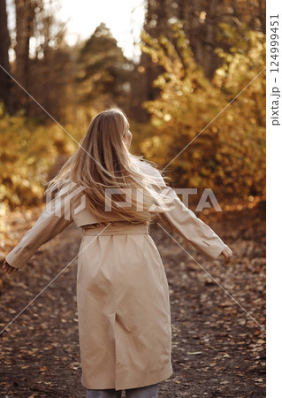Woman Twirling in Autumn Forest Path. Rear View Woman Twirling in Autumn Forest Path. Rear View 124999451