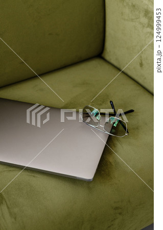 Closed Laptop with Eyeglasses on Green Sofa, Minimal Workspace Closed Laptop with Eyeglasses on Green Sofa, Minimal Workspace 124999453