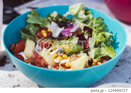 This colorful salad features fresh greens, tomatoes, corn, nuts, and pineapple. 124999727