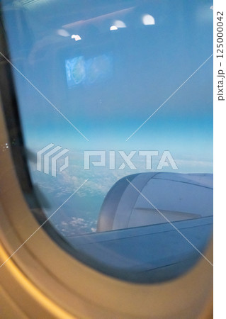 Sky and cloud seen through the window of airplane, with the plane wing 125000042