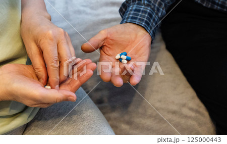 Hands exchanging medicine during a health check in a cozy living room setting Hands exchanging medicine during a health check in a cozy living room setting 125000443