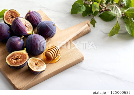 Fresh figs and honey dripping from wooden dipper on cutting board 125000685