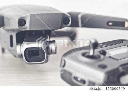 Close-up of a gray quadcopter drone with its remote control, showcasing advanced technology for aerial photography and videography 125000849