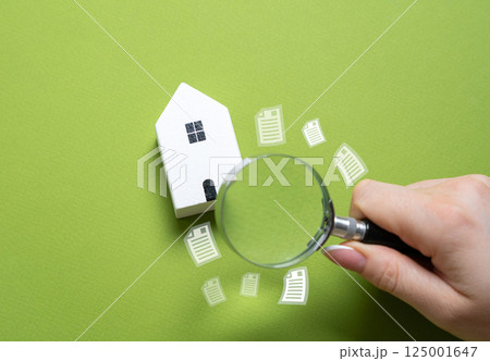 Lawyer checks a house with a magnifying glass. Checking legal documents for real estate. Ownership legitimacy. Examine contracts, titles, deeds, zoning laws, and legal clauses before purchase or sale. 125001647