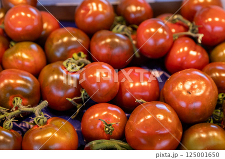 Vibrant heirloom tomatoes with a glossy texture and deep colors displayed at a farmers market. Ideal 125001650