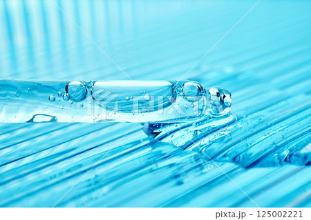 Serum in a pipette on a blue ribbed background. Serum in a pipette on a blue ribbed background. 125002221