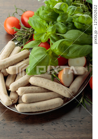Traditional Bavarian white sausages with basil and tomatoes. 125002622