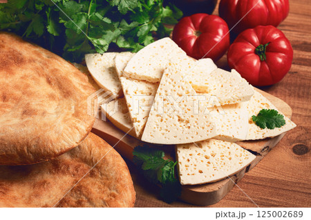 Georgian sliced cheese,on a wooden chopping board, with tomatoes with herbs and lavash, rustic style, Georgian cuisine, no people Georgian sliced cheese,on a wooden chopping board, with tomatoes with herbs and lavash, rustic style, Georgian cuisine, no people 125002689