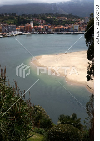 Scenic view of Ribadesella town and sandy beach with cloudy mountain backdrop, Asturias, Spain Scenic view of Ribadesella town and sandy beach with cloudy mountain backdrop, Asturias, Spain 125002703