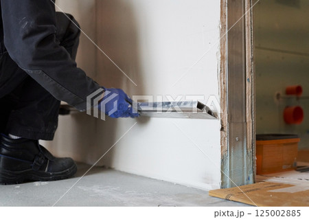 Hands with a metal rule. Apartment renovation. Leveling the plastered wall. Home improvement. Men's hands in protective gloves with a building rule. High quality photo Hands with a metal rule. Apartment renovation. Leveling the plastered wall. Home improvement. Men's hands in protective gloves with a building rule. High quality photo 125002885