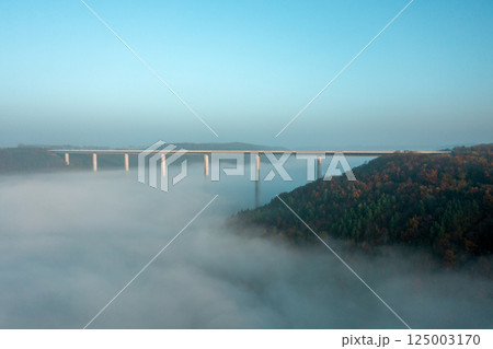 Highway bridge over dense fog, drone aerial view, at sunrise in Germany Highway bridge over dense fog, drone aerial view, at sunrise in Germany 125003170
