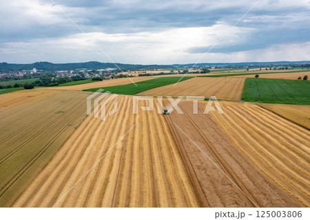 Aerial image with a combine harvesting crop in Germany in the evening Aerial image with a combine harvesting crop in Germany in the evening 125003806