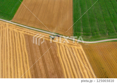 Drone image with a combine harvesting crop in Germany in the evening 125003810