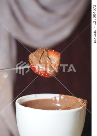 Enjoying chocolate-covered strawberries at a dessert party 125004072