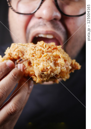 Enjoying a tasty piece of fried chicken in evening light 125004165