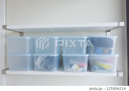 Organization of storage containers on a white shelf in a tidy space 125004214