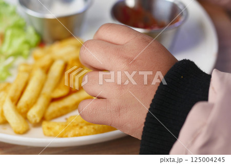 Child enjoying fries and dipping sauces at casual dining restaurant 125004245