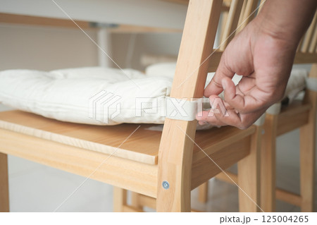 Adjusting chair cushion at home for comfortable seating experience Adjusting chair cushion at home for comfortable seating experience 125004265