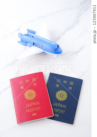 日本のパスポート(10年用赤色と5年用紺色)と飛行機で、長期休暇に海外旅行を計画しているイメージ 日本のパスポート(10年用赤色と5年用紺色)と飛行機で、長期休暇に海外旅行を計画しているイメージ 125007911