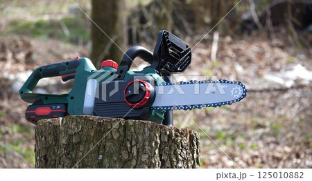 Modern cordless chainsaw is displayed, ready for use in various woodworking and forestry tasks. Modern cordless chainsaw is displayed, ready for use in various woodworking and forestry tasks. 125010882