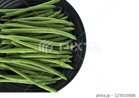 Fresh green beans resting on a black plate, ready to be cooked 125010886